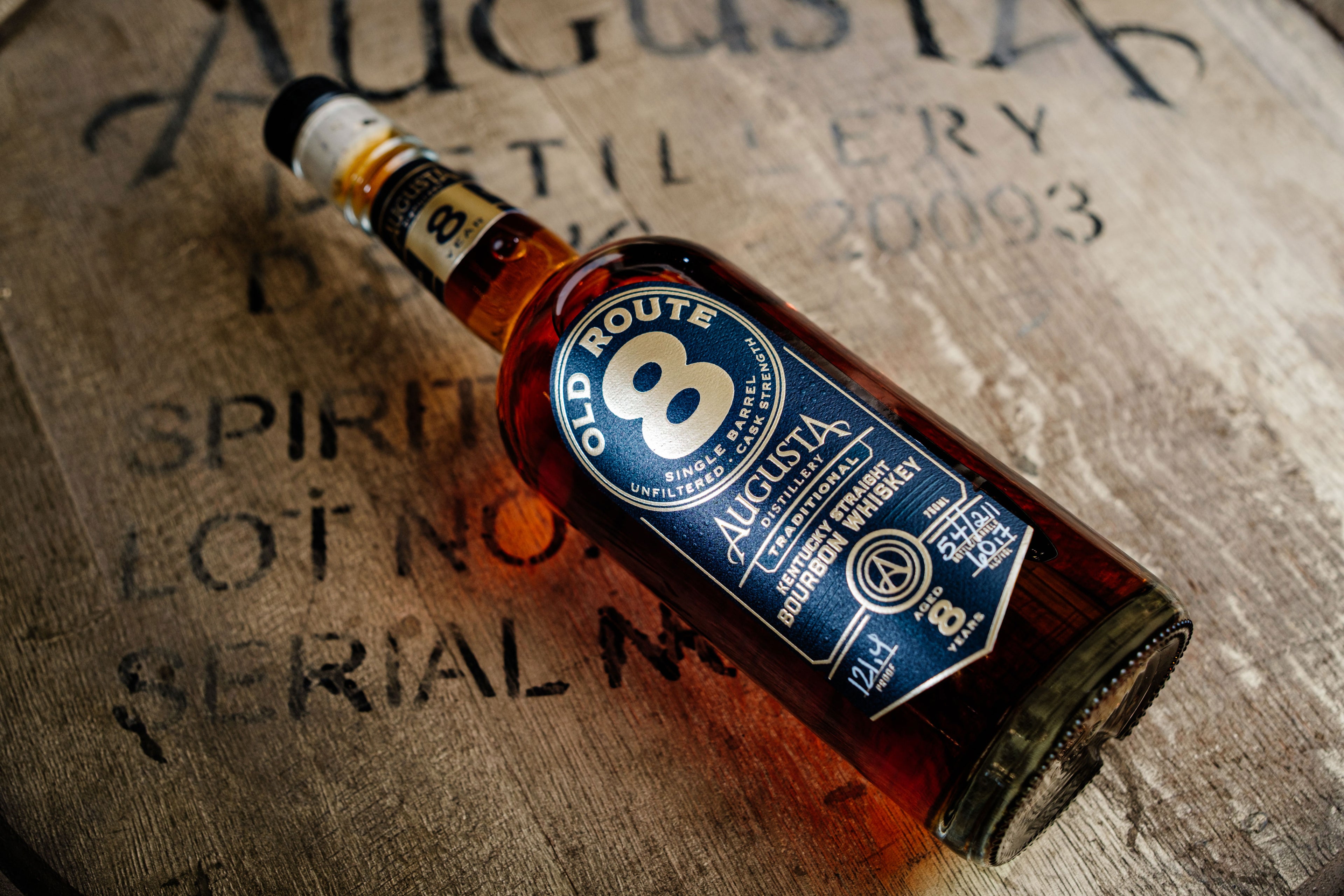 A bottle of Augusta Distillery Old Route 8 Single Barrel Unfiltered Cask Strength Kentucky Straight Bourbon Whiskey 750ml 8 Years over a bourbon barrel