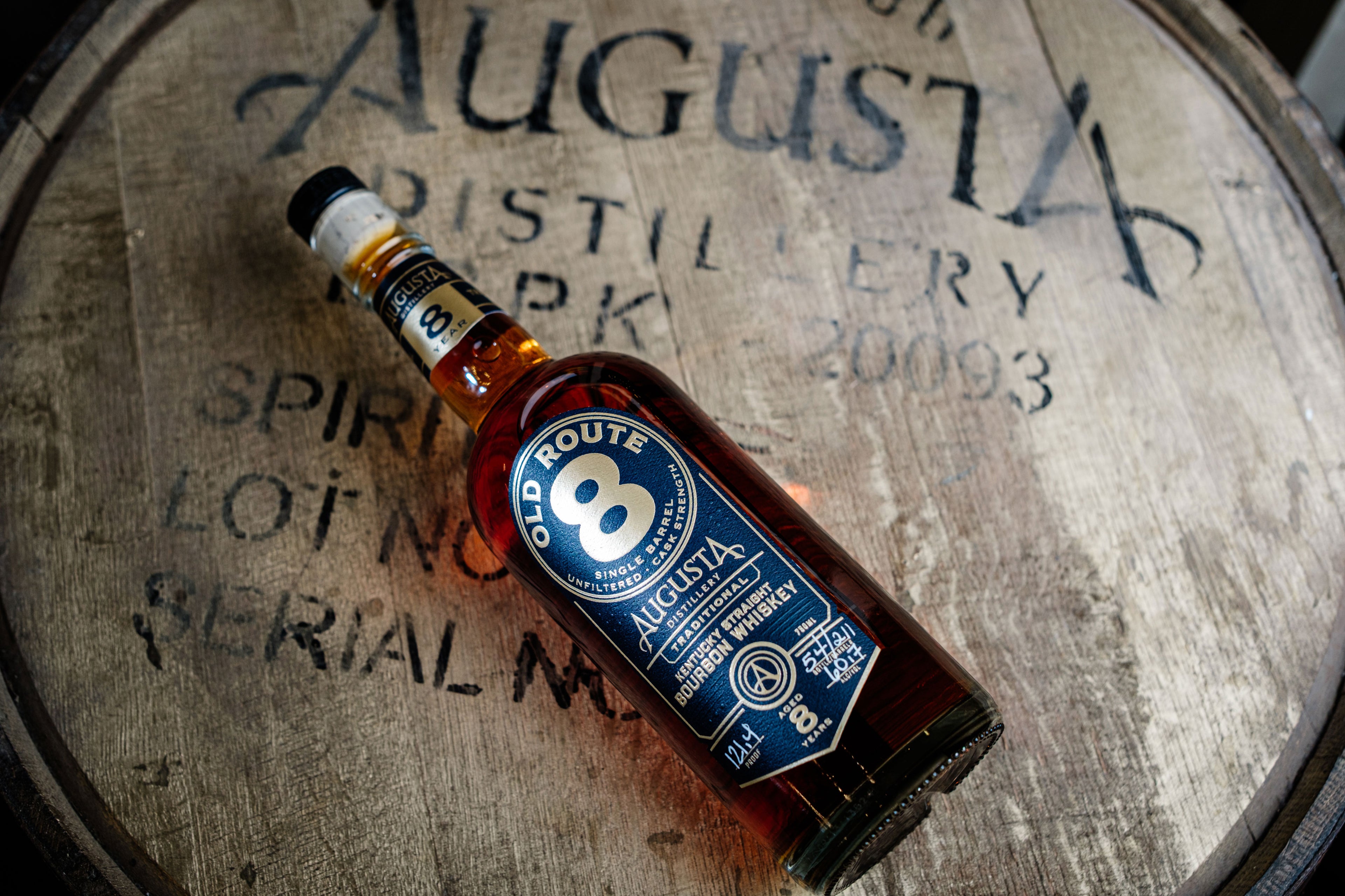 A bottle of Augusta Distillery Old Route 8 Single Barrel Unfiltered Cask Strength Kentucky Straight Bourbon Whiskey 750ml 8 Years over a bourbon barrel