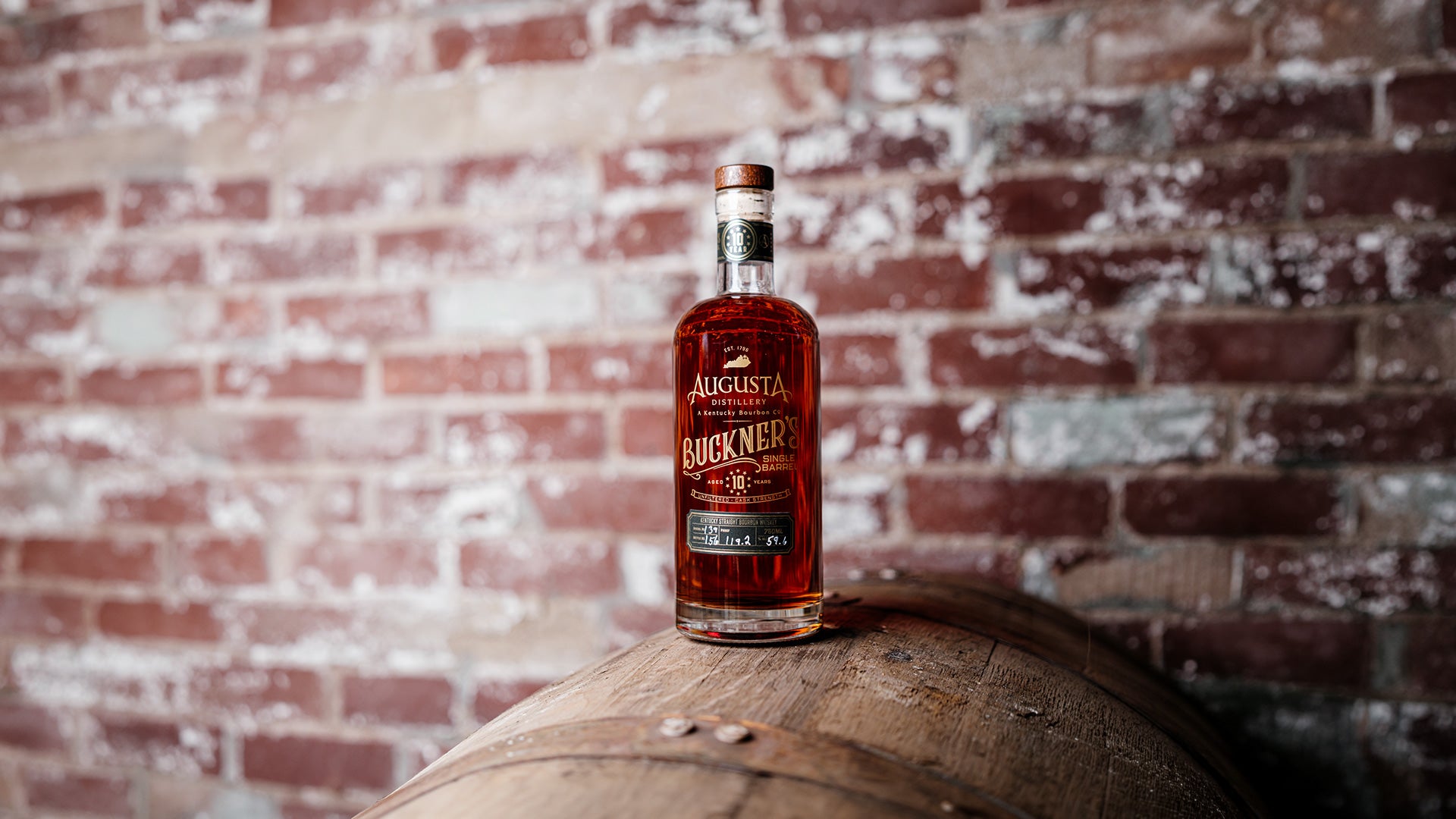 A bottle of Augusta Distillery Buckner's 10 Single Barrel Unfiltered Cask Strength Kentucky Straight Bourbon Whiskey 750ml 10 Years over a bourbon barrel